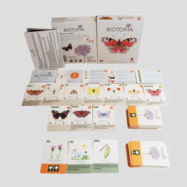 All components of BIOTOPIA laid out, including flower and butterfly cards, mission cards, and game board, inviting players to attract butterflies.